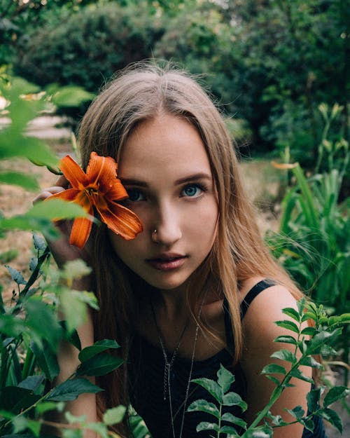 Young woman near orange blooming flower