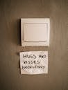 Lighting switch on wall near attached paper with Hugs and Kisses Emergency inscription