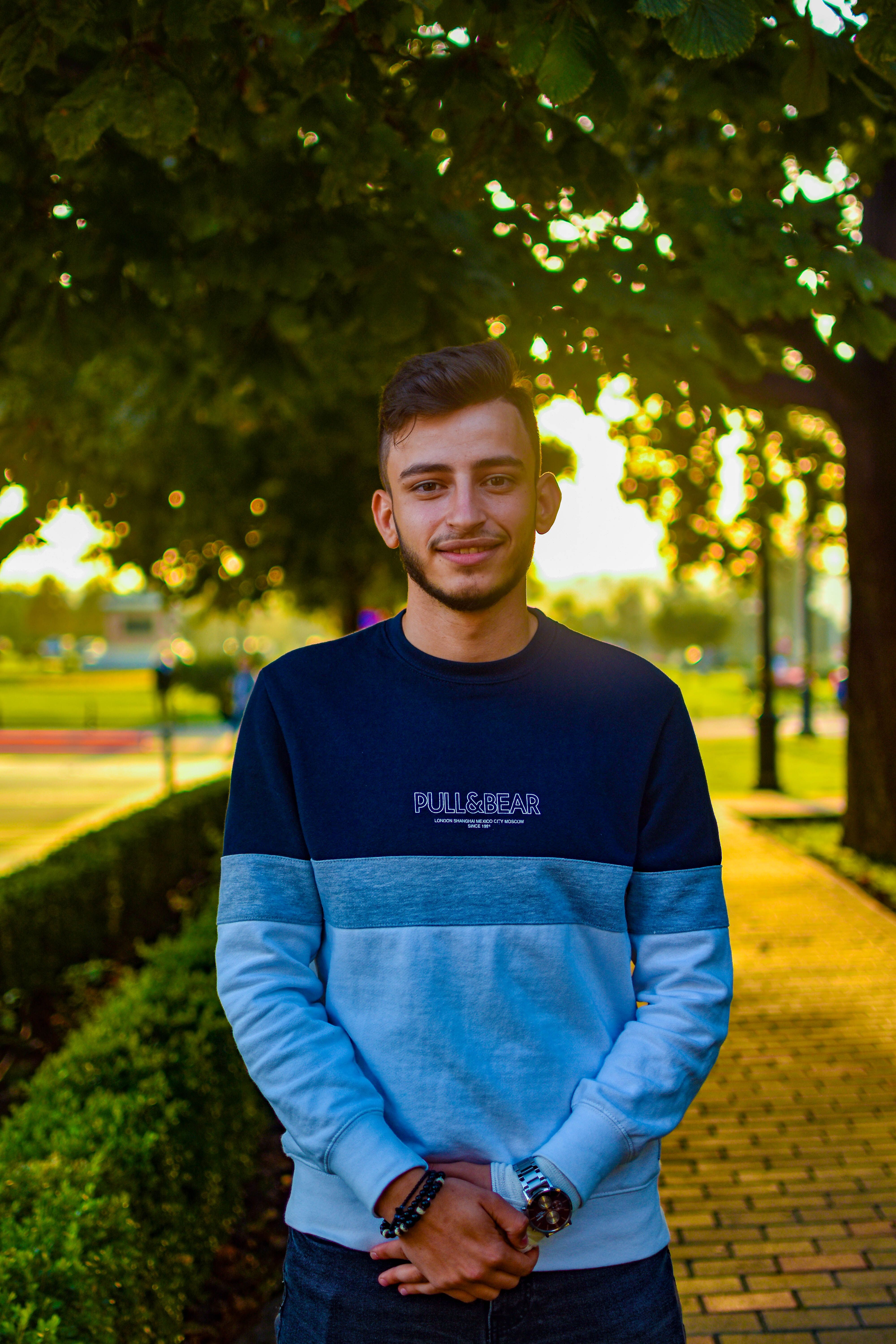 Portrait of a smiling young man with a stylish look outdoors during golden hour.