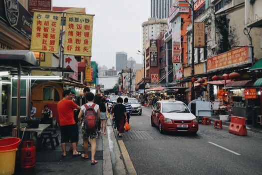 Vibrant street scene in Kuala Lumpur's Chinatown showcasing bustling activity and colorful signage.