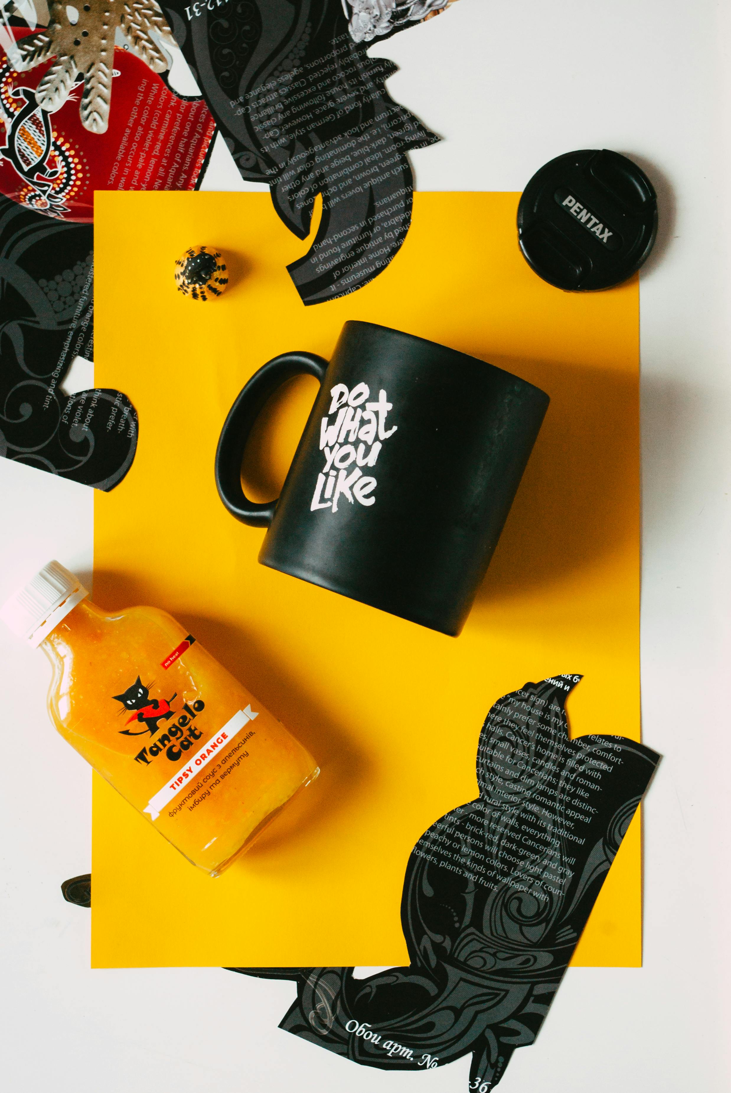 mug and juice bottle arranged on table with paper clippings