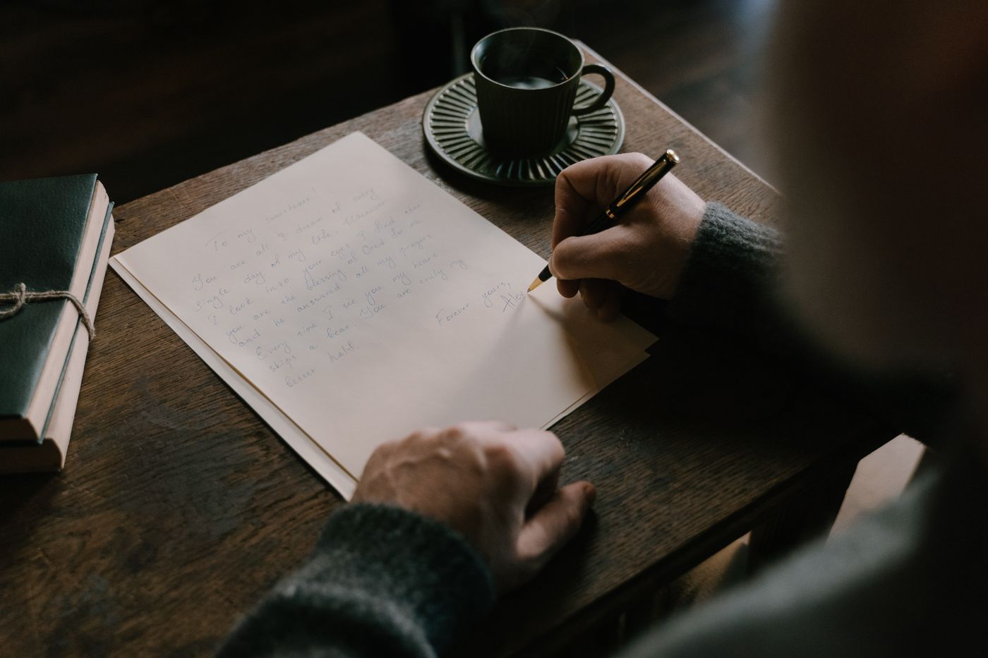 Une personne écrit une lettre sur un bureau en bois