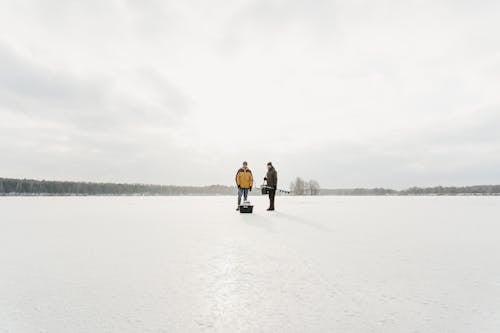 Men Standing in Frozen Lake to Explore