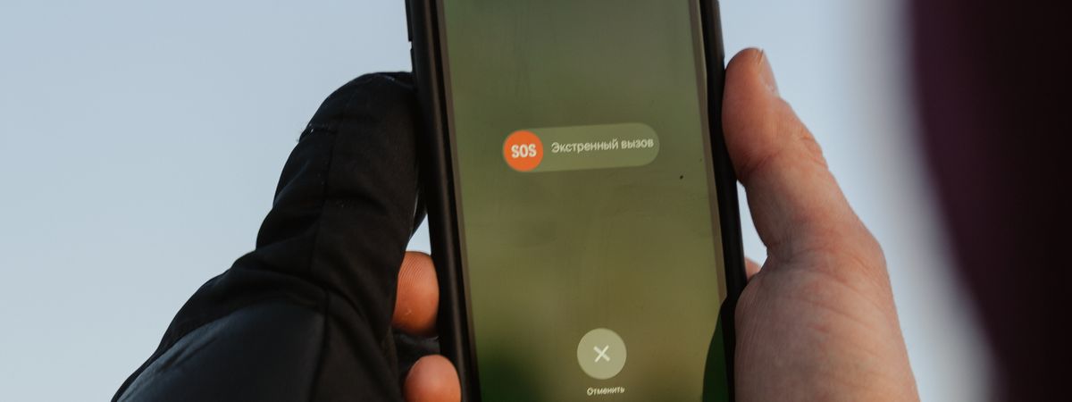 Persona con guantes sujetando un móvil con la opción de llamada de emergencia