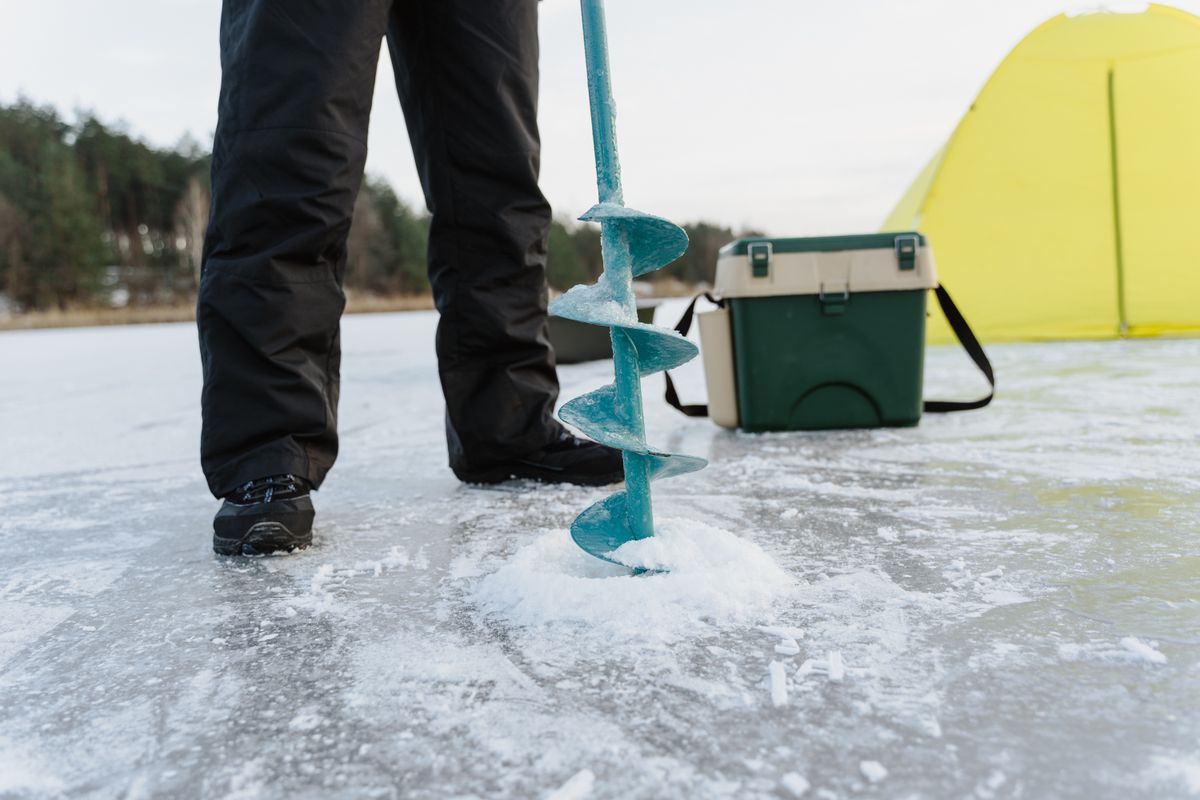 Ice fisherman with auger drilling