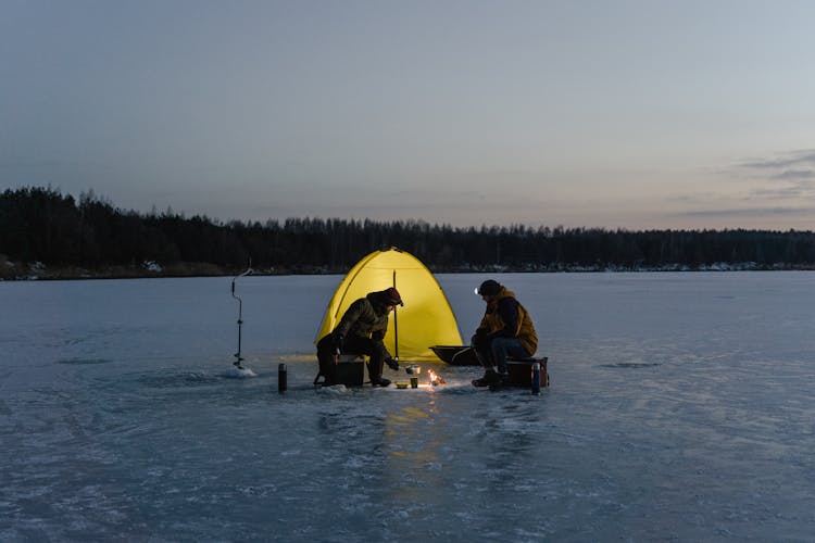 Persons Cooking Near A Tent At Dusk