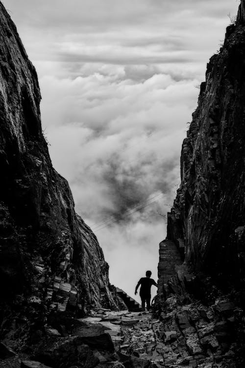 Silhouette of Man Walking Between Two Cliff