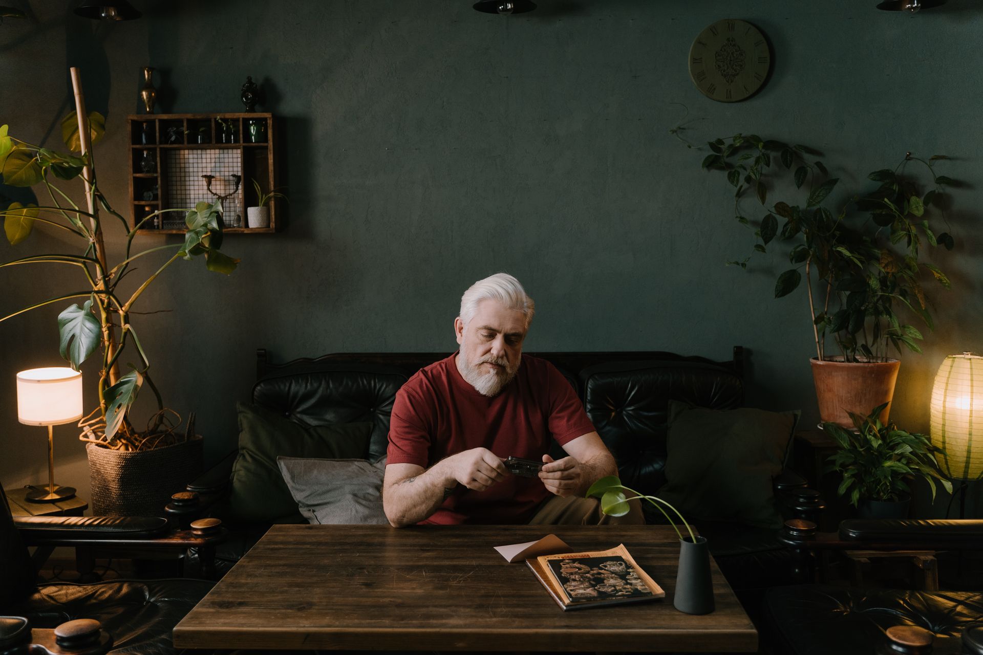 Senior man with beard enjoying unboxing a gift at home in a cozy living room setting.