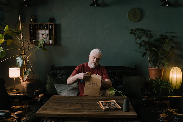 An Elderly Man Putting The Socks Inside The Brown Envelope