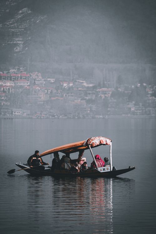 Free A group enjoys a tranquil boat ride on a misty lake surrounded by distant mountains. Stock Photo