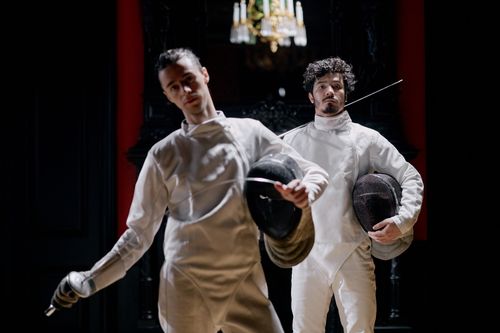 Free Two fencers in action during an intense indoor match, showcasing skill and agility. Stock Photo