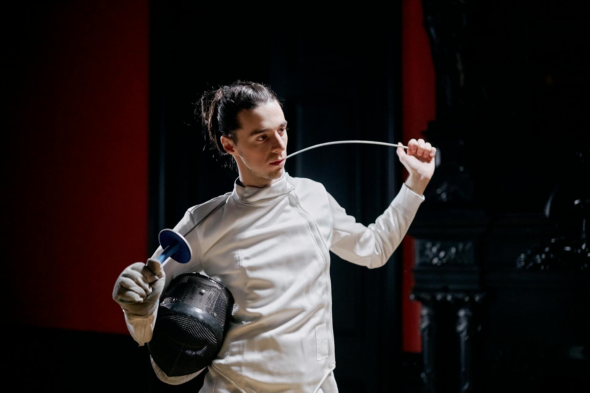 A Man in White Overalls and Holding Fencing Gears