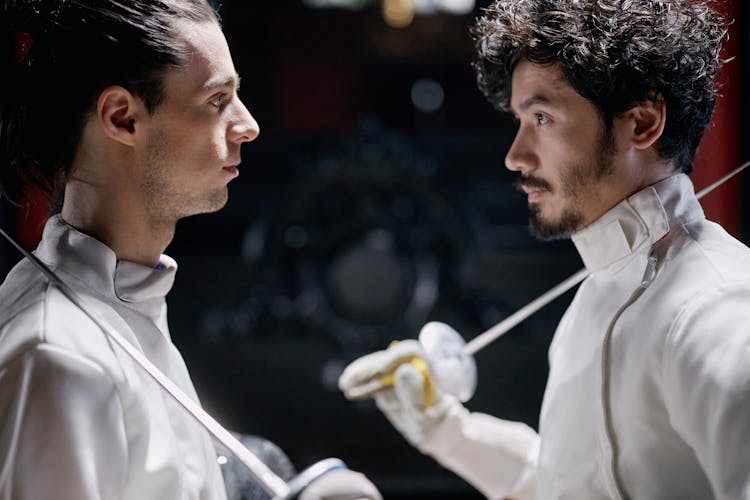 Two Men Facing Each Other Holding Fencing Swords