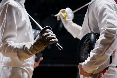 Free Two men in protective fencing gear prepare for a duel, highlighting athletic skill and precision. Stock Photo