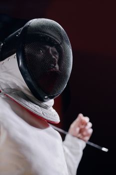 Close-up of a fencer wearing a protective mask and holding a foil, ready for action.