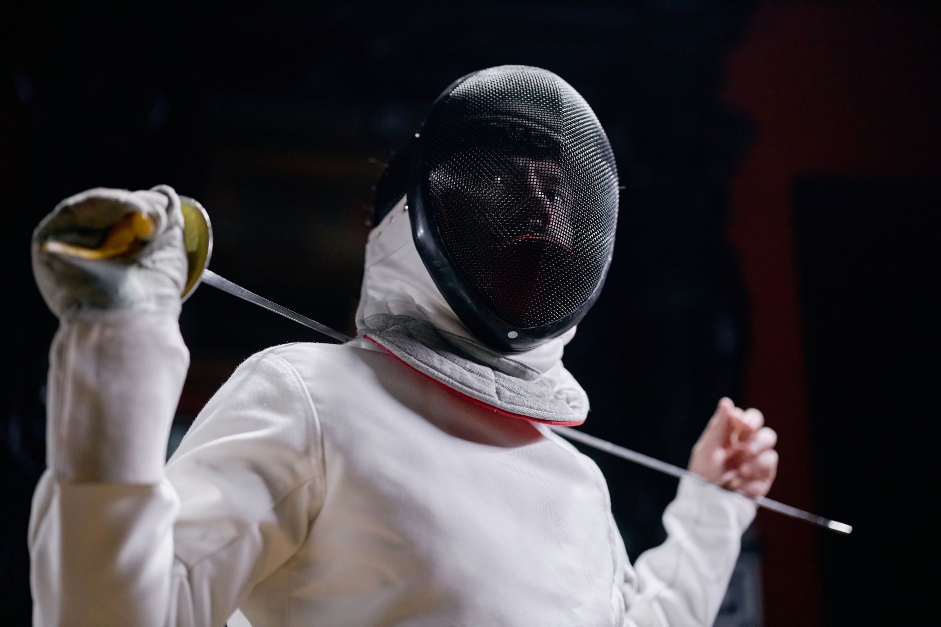 Fencer in full gear poised with an epee sword, displaying readiness and grace.