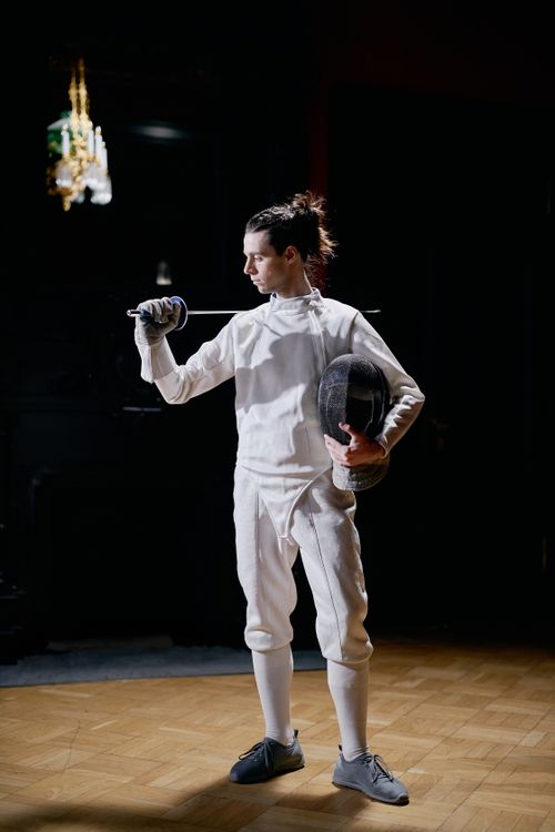 Free A fencer in full gear posing indoors with a sword, conveying focus and determination. Stock Photo