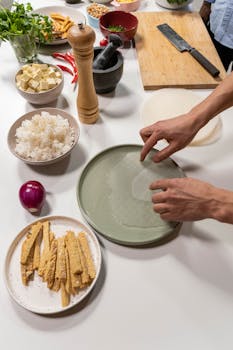 Hands carefully preparing spring rolls with fresh ingredients on a kitchen counter.