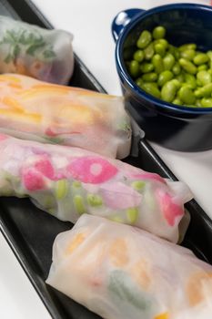 Delicious handcrafted spring rolls with colorful vegetables served with edamame beans.