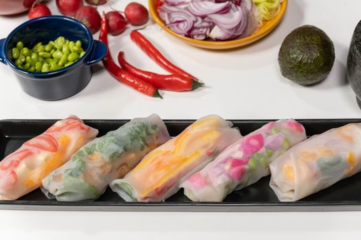 Colorful vegan spring rolls with fresh vegetables on a black plate; perfect for healthy living.