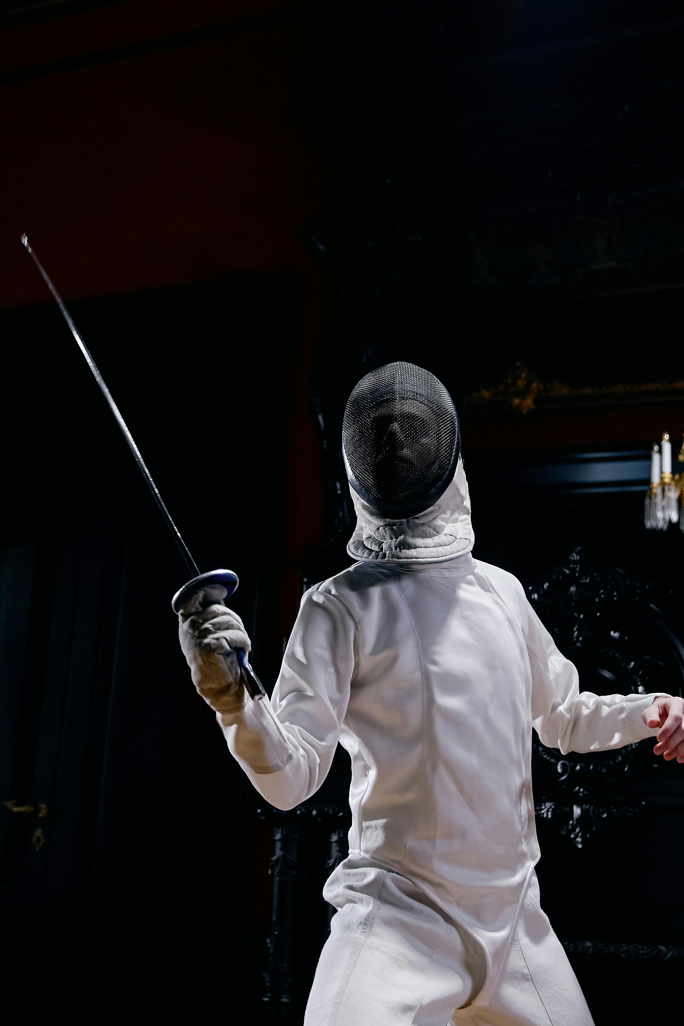 a fencer in a fencing uniform holding a foil