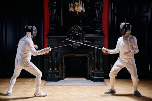 People in White Long Sleeves and White Pants Holding Silver Metal Rod