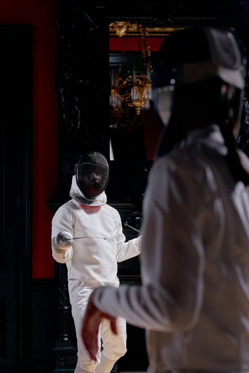 Free Two fencers in action during an indoor fencing match, showcasing skill and precision. Stock Photo