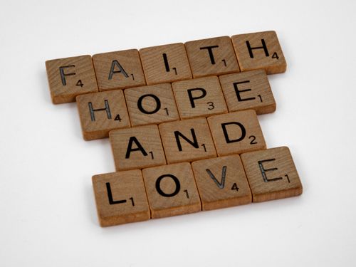 Free Scrabble tiles arranged to spell 'Faith Hope and Love' on a white background, perfect for positivity themes. Stock Photo