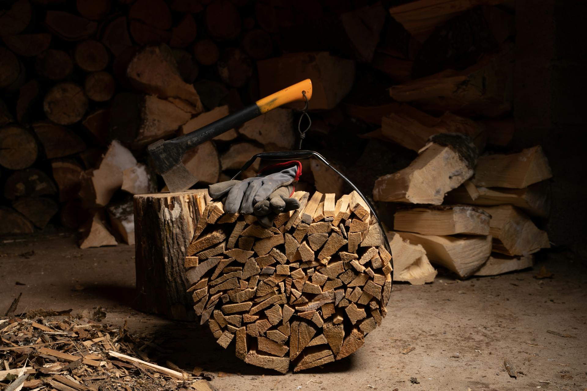 Chopped firewood in a rustic shed with an axe and gloves, perfect for winter heating.