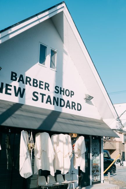 Low angle of traditional barber shop in aged house located in town against cloudless blue sky