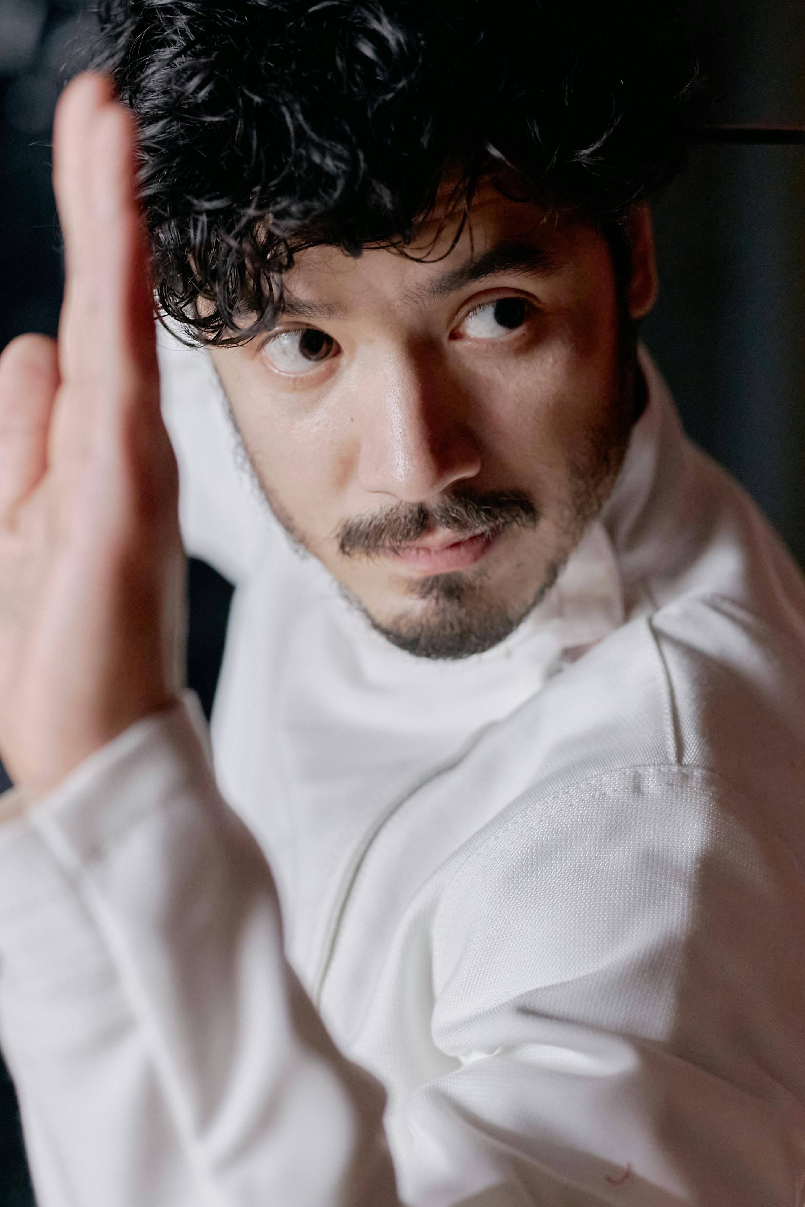 Close-up of a man in a white martial arts uniform focusing intently.