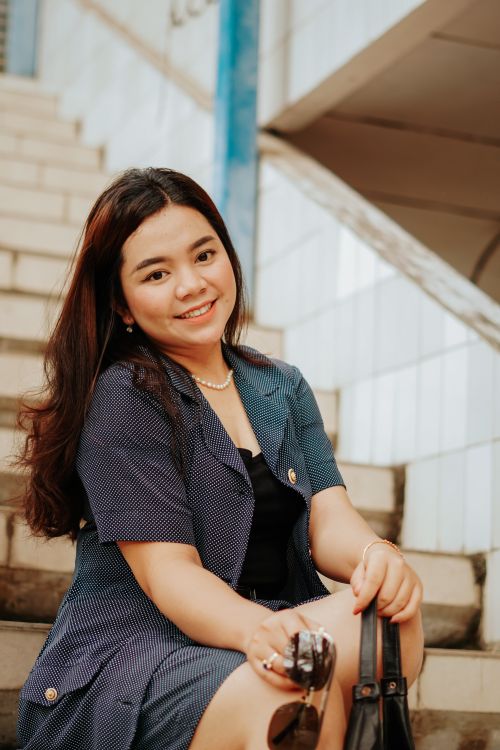 Free Cheerful woman sitting on stairs in Cirebon, Indonesia, with fashionable attire. Stock Photo