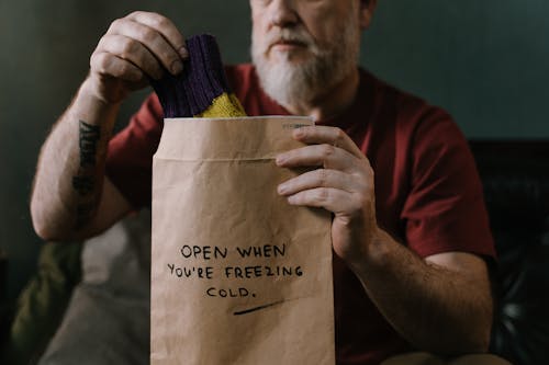 Elderly man Putting A Pair of Socks In A Brown Envelope With Message