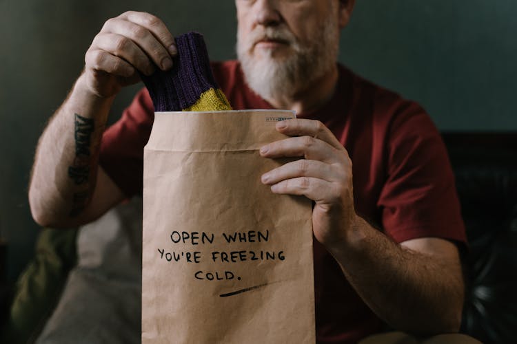 Elderly Man Putting A Pair Of Socks In A Brown Envelope With Message