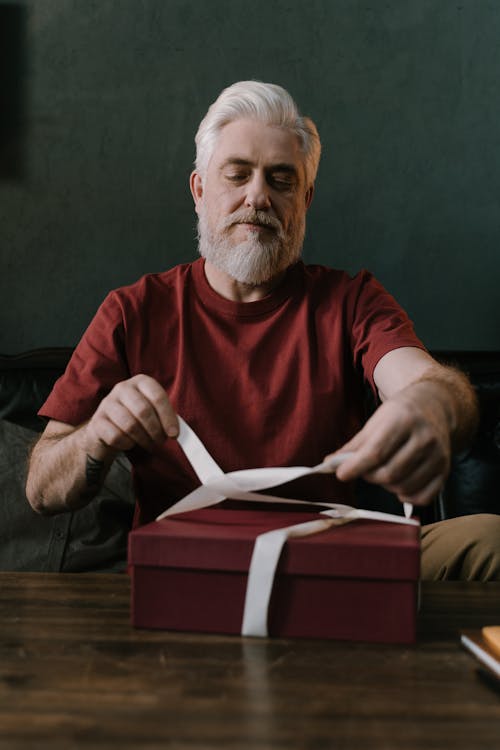 Free An Elderly Man Tying Ribbon on a Gift Box Stock Photo