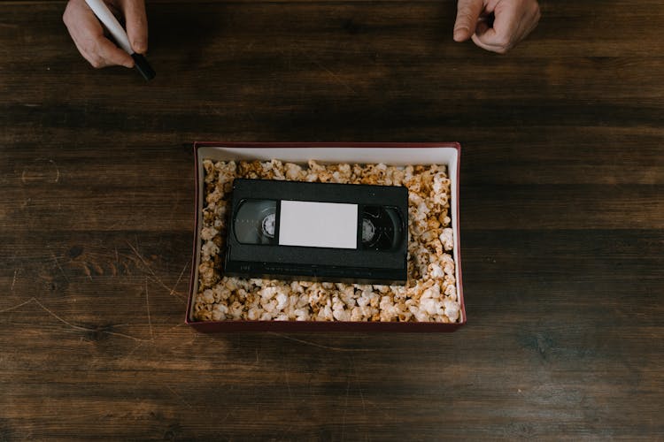 Popcorn And A Vhs Tape Inside A Cardboard Box