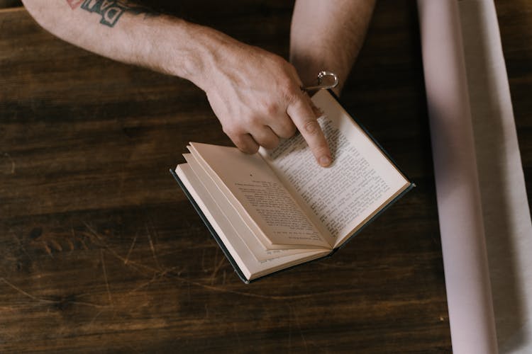 A Person Pointing Words Of A Book Using Index Finger