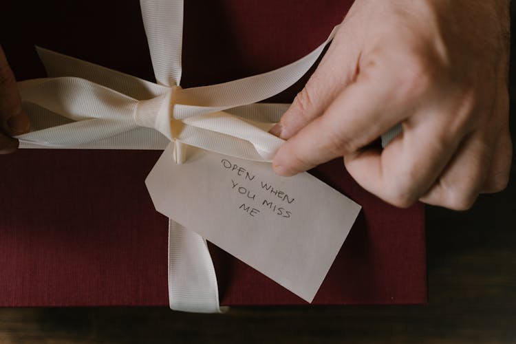 Tying A Ribbon With Handwritten Words On A Paper Tag