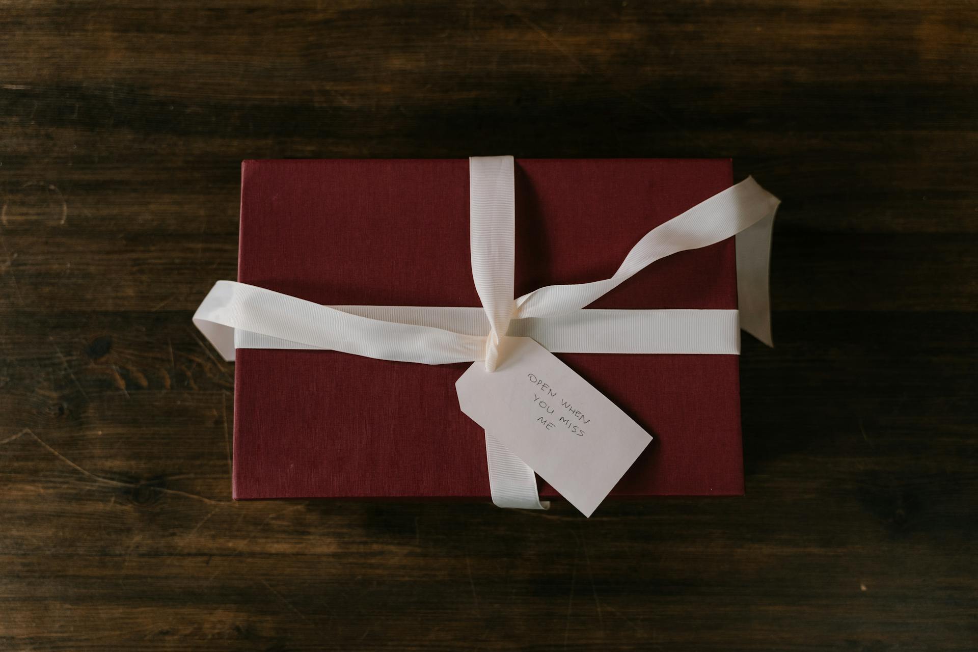 Box with White Ribbon on a Wooden Surface