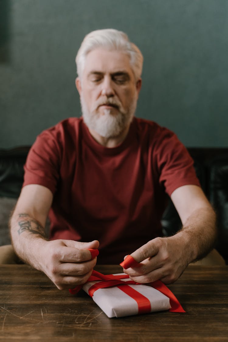 A Man With White Hair Tying A Red Ribbon