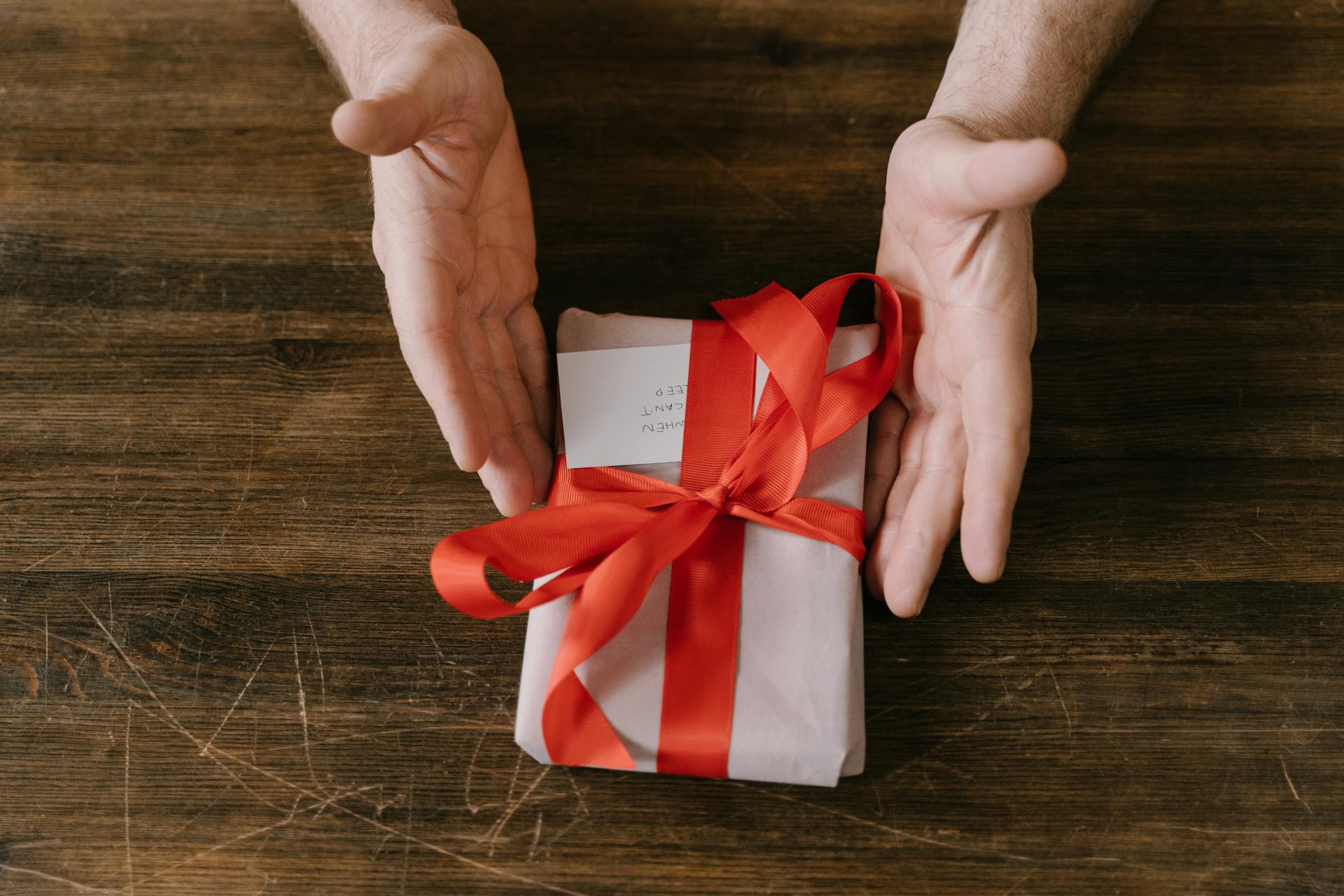 A Person Holding a Gift with Red Ribbon