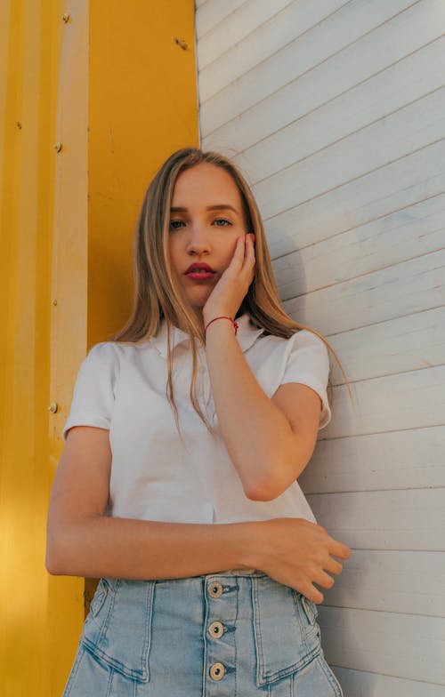 Stylish young female millennial touching face and looking at camera on street