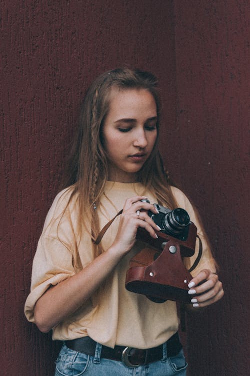 Young lady putting vintage photo camera into leather case
