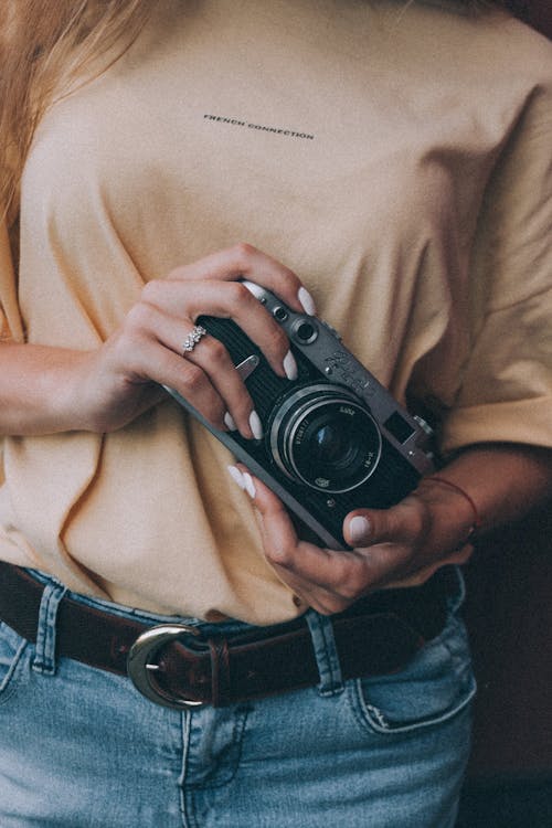 Crop stylish female photographer holding retro camera in hands