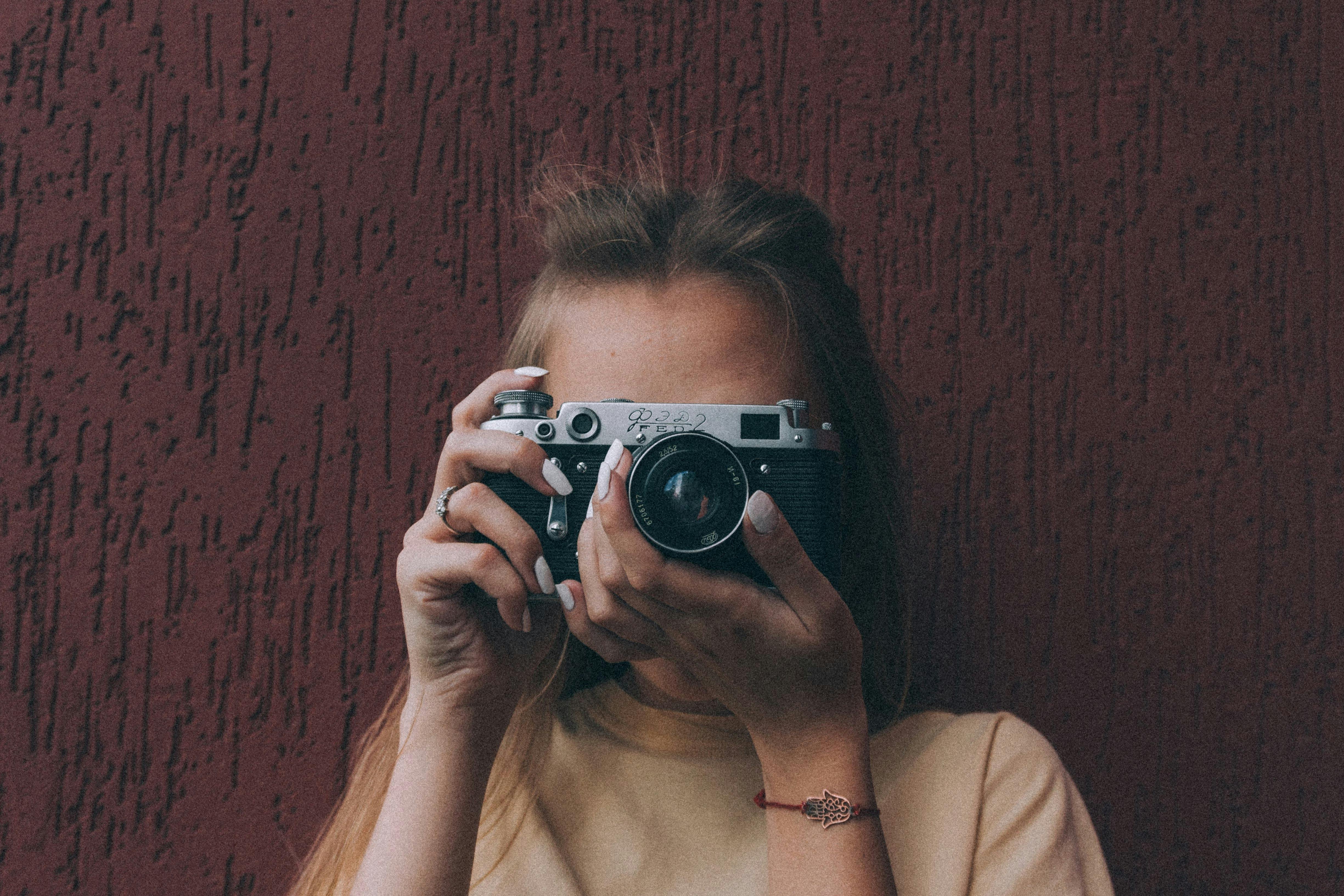 Unrecognizable slender lady taking instant photos on vintage camera ...