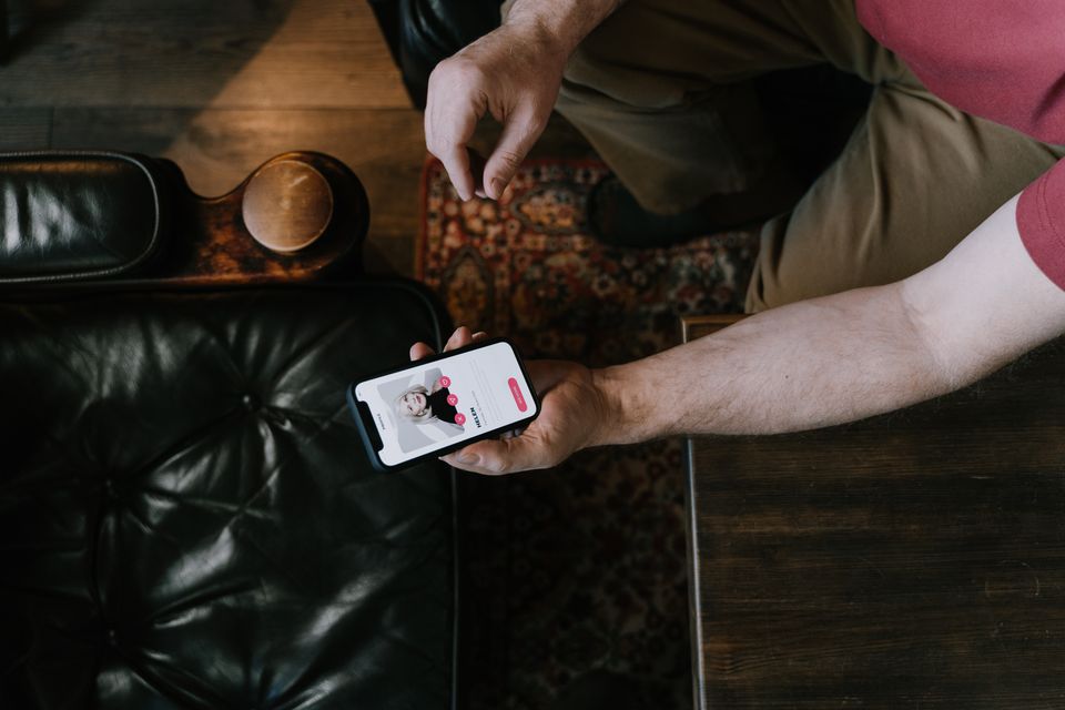 A person holding a smartphone with a dating app open