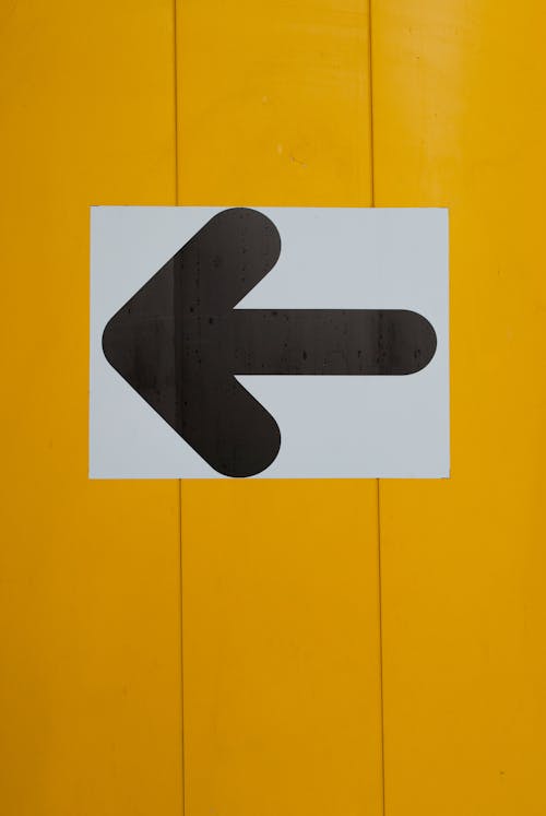 Foto profissional grátis de direção, flecha, parede amarela