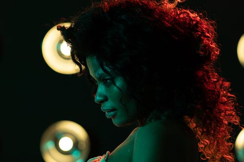 Free Artistic profile portrait of a young woman with curly hair under vivid lighting. Stock Photo