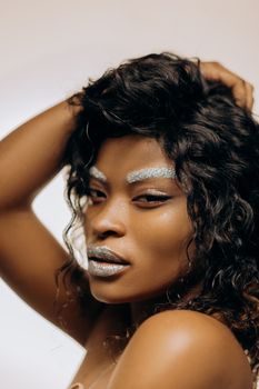 Close-up of a stylish woman with silver makeup posing confidently.