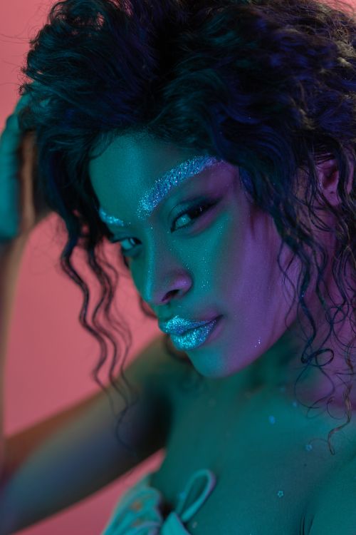 Free A stunning portrait of an African American woman with glitter makeup, curly hair, and a sensual expression. Stock Photo
